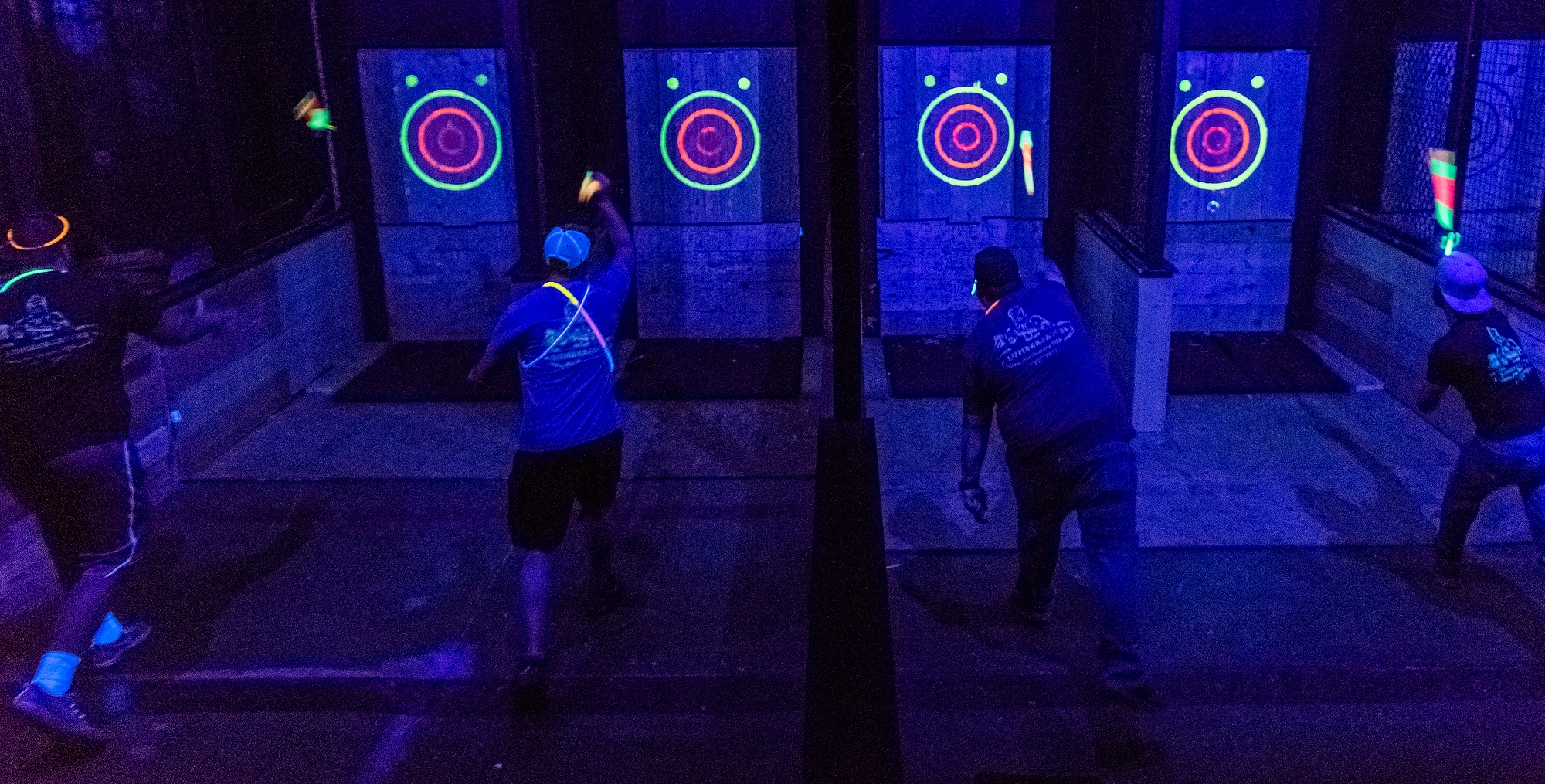 Blacklight axe throwing lanes glowing with neon targets